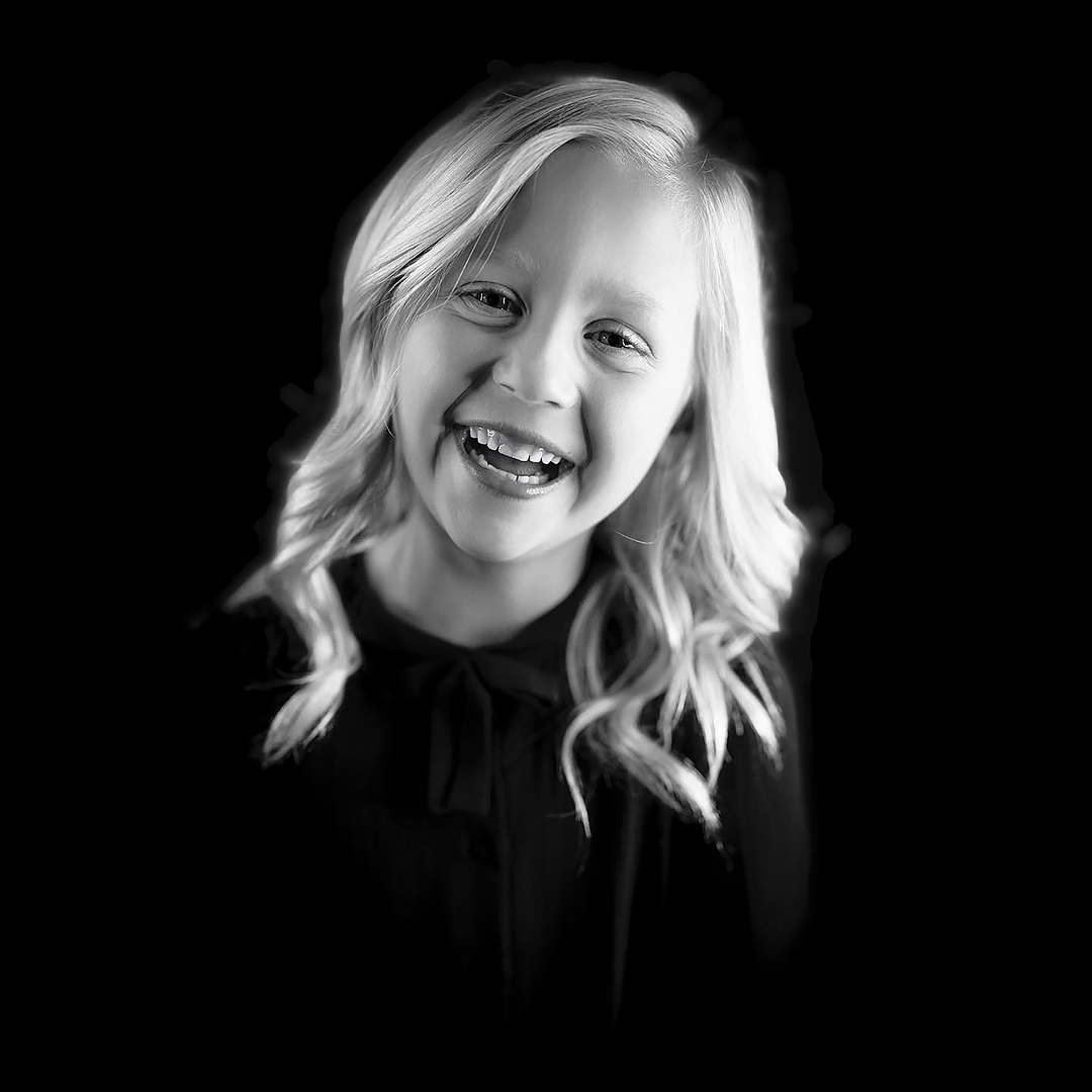 blonde kid photographed in black and white in front of a black background