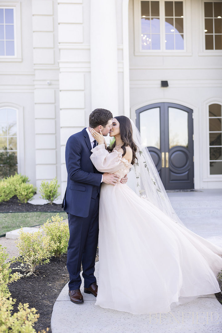 bride and groom laughing and kissing outside The Hillside Estate in Cross Roads Texas.