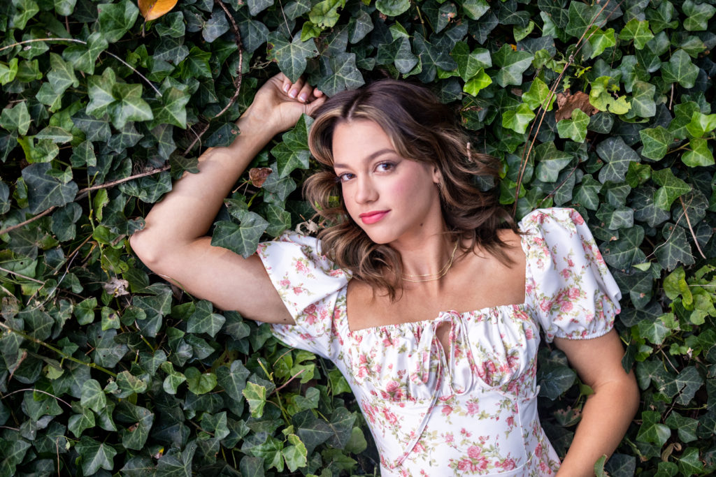 Cute high school Senior Pictures in a Bed of Ivy covered ground wearing floral dress in Tulsa OK