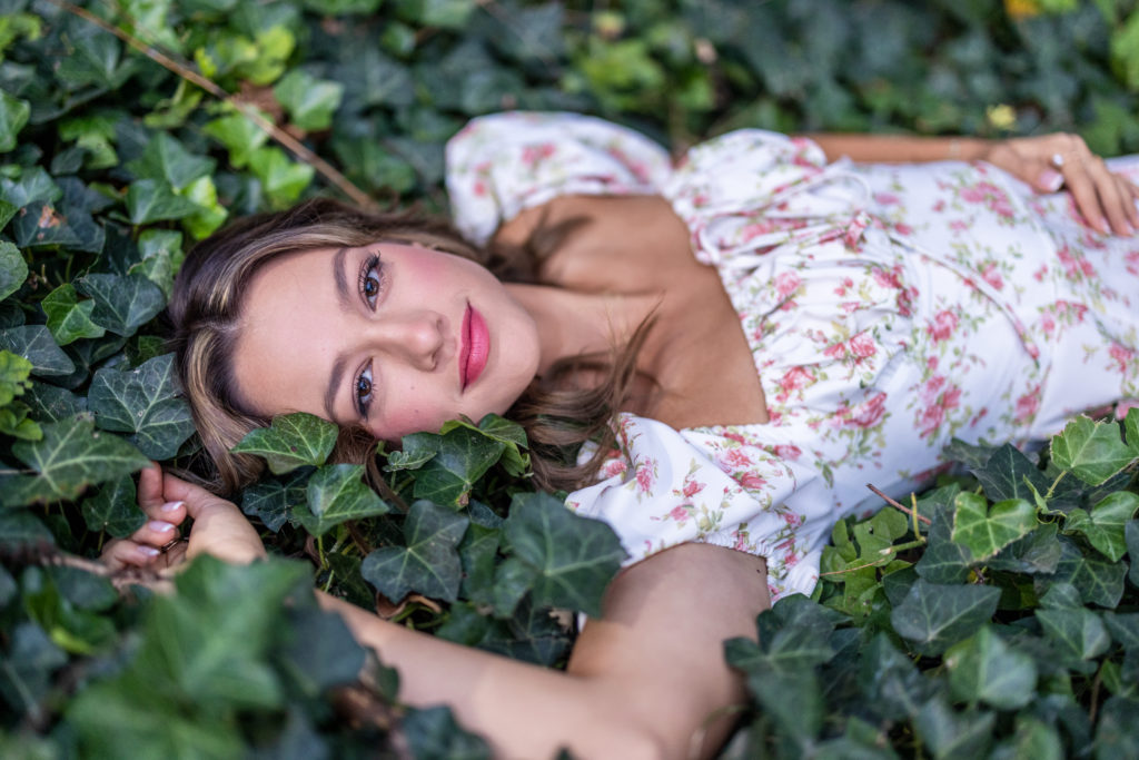 Cute high school Senior Pictures in a Bed of Ivy covered ground wearing floral dress in Tulsa OK