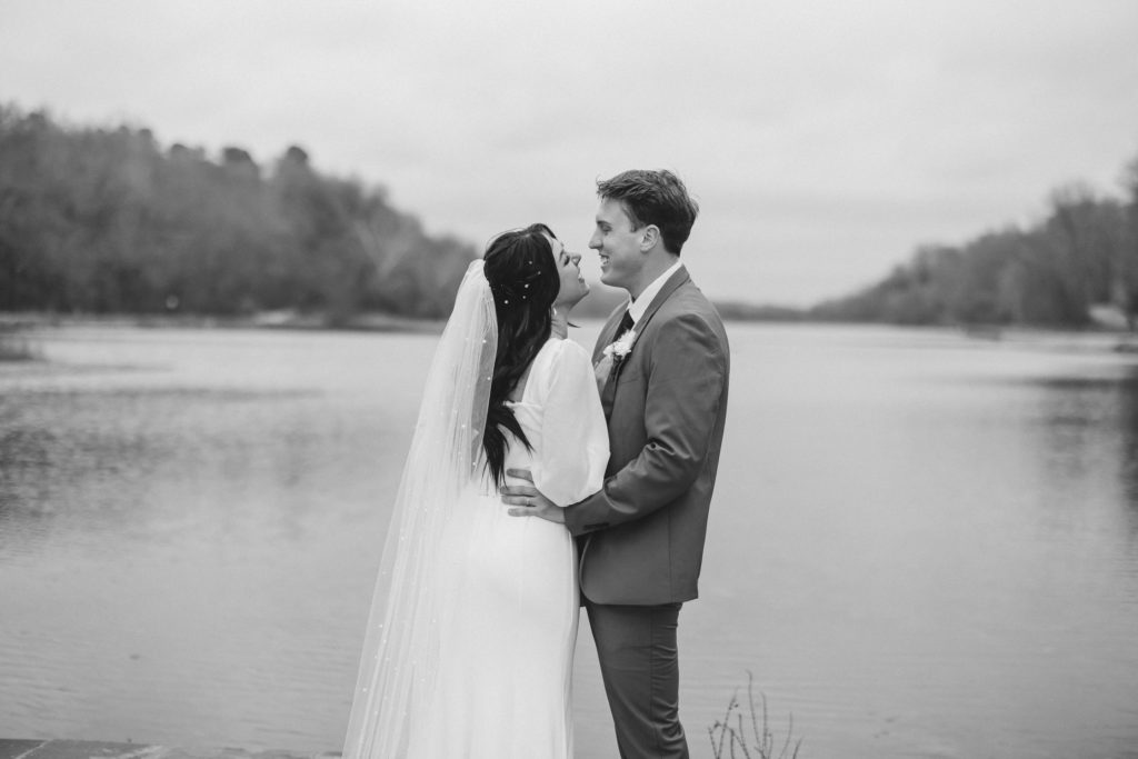 Timeless B+W Wedding Portraits of a bride and groom kissing at the edge of a lake in Northwest Arkansas.