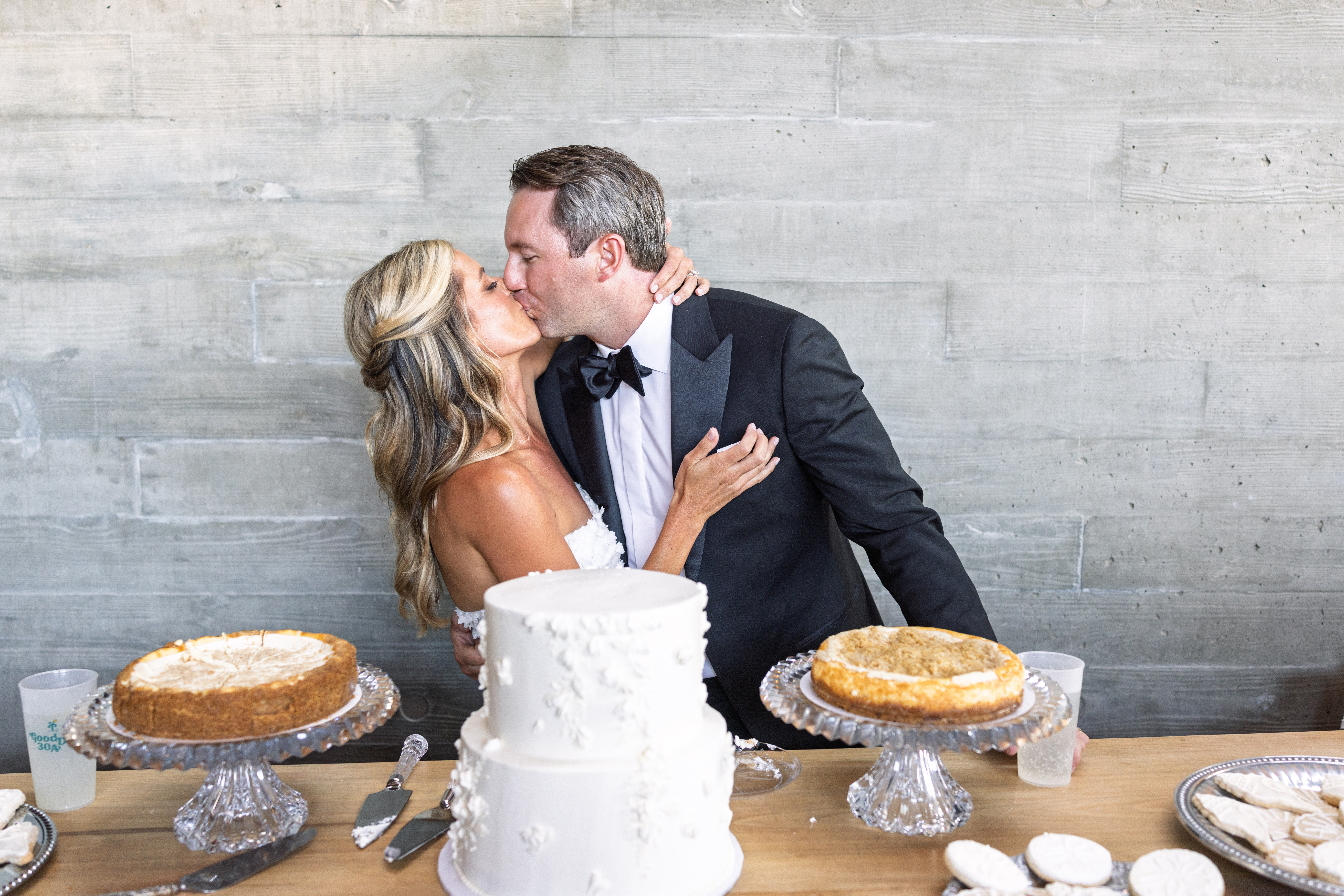 Bride and groom kissing beside cake at St. Catherine’s at Bell Gable wedding