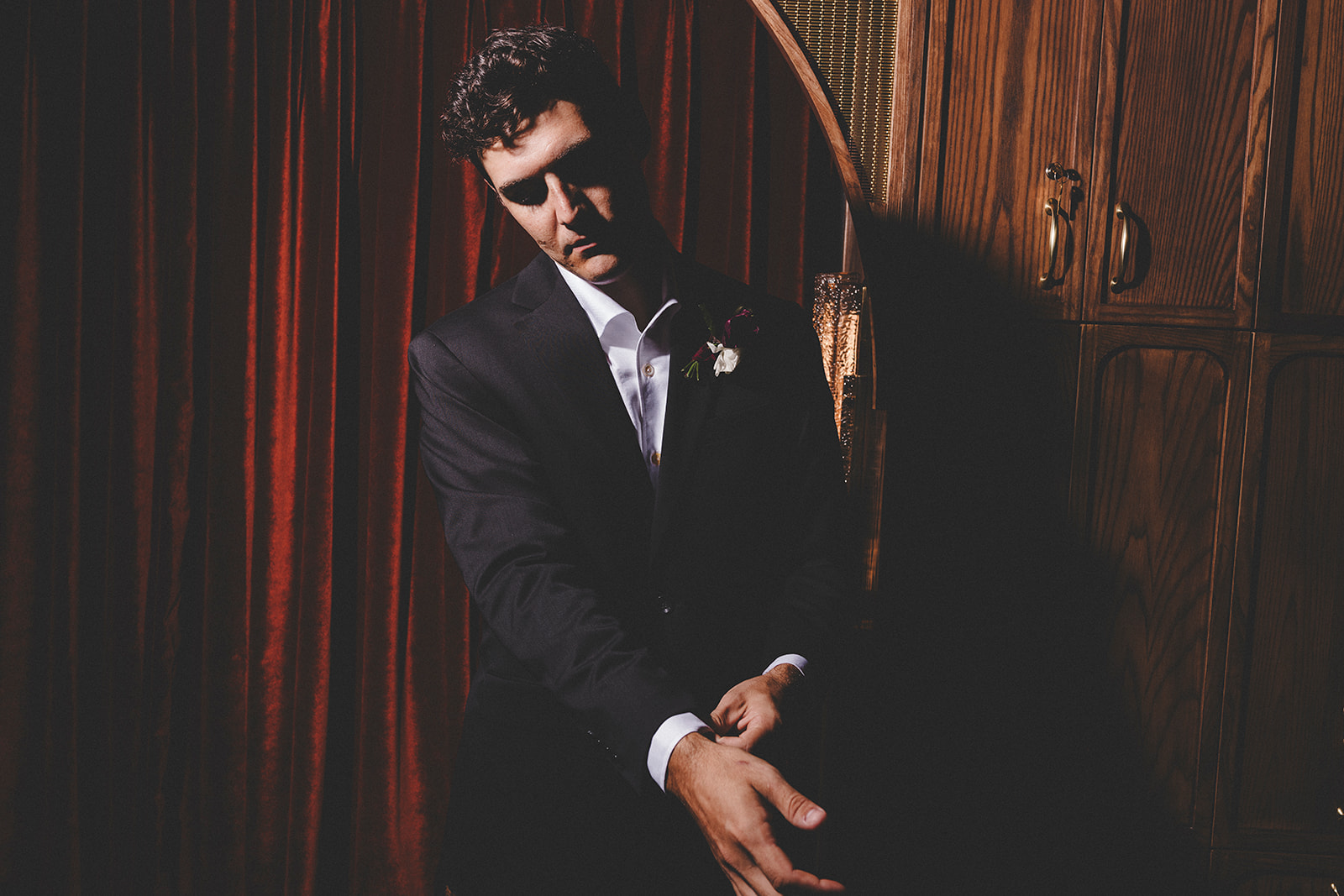 Moody groom portrait with red velvet and dark wood at Hotel Vin Rogers.