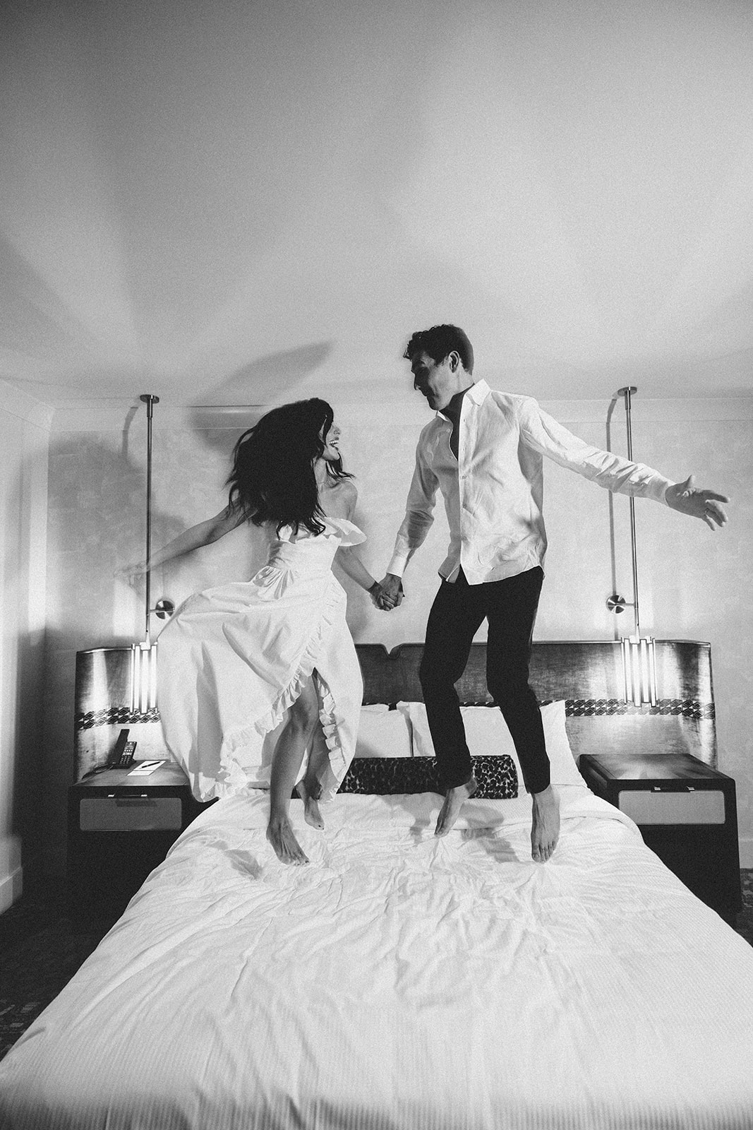 Bride and groom jumping on the bed in their Hotel Vin Rogers room after the wedding.