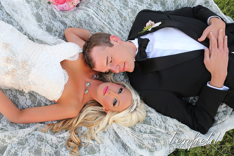 bride and groom lying down on lace on the ground