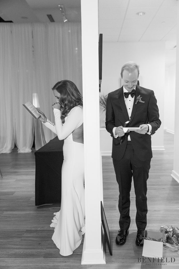 the bride cries while opening a letter from her soon-to-be husband on one side of a wall; the groom smiles on the other. this is a unique first look idea where you don't actually see your bride or groom.