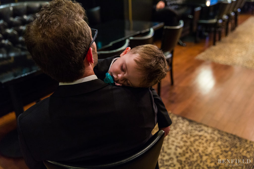 a ring bearer falls asleep before the wedding ceremony with a pacifier in his mouth
