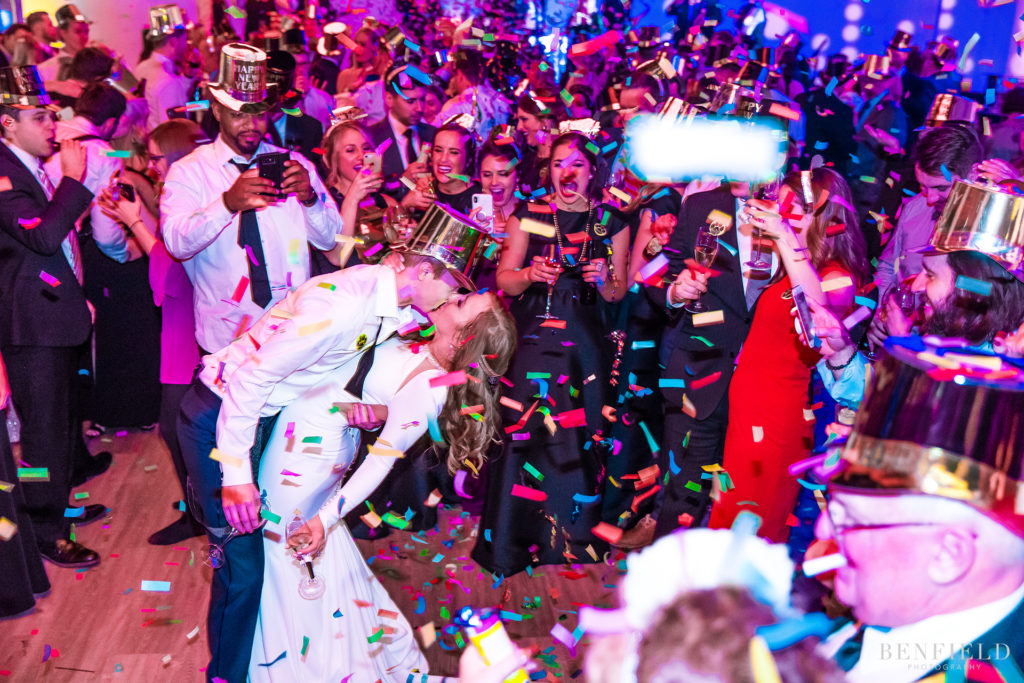a Confetti fills the room during a midnight kiss by bride and groom on new years eve concluding their wedding reception at the Gallery Event Space in Kansas City Power and Light District on new years eve. kiss by bride and groom on new years eve concluding their wedding reception at the Gallery Event Space in Kansas City Power and Light District on new years eve.