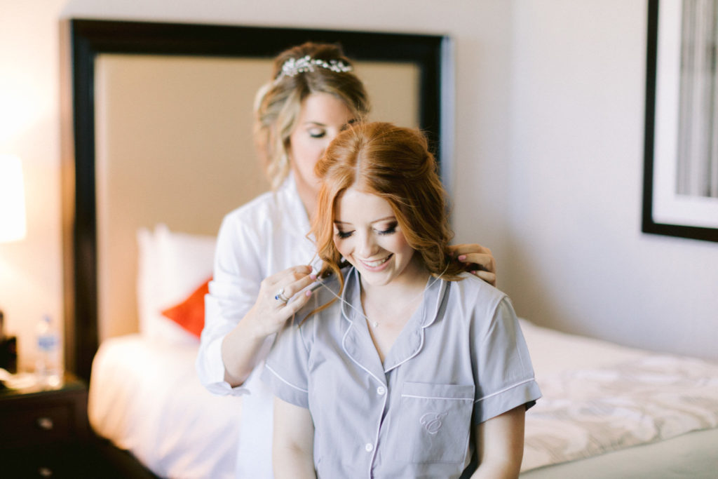 new stepmom putting necklace on daughter during the wedding day
