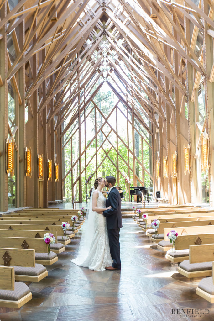 bride and groom kissing in a glass wedding chapel