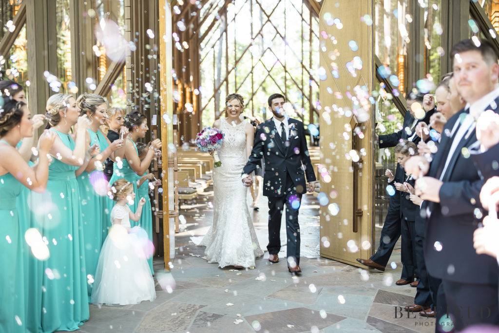 bride and groom leaving glass chapel wedding with bubble leave