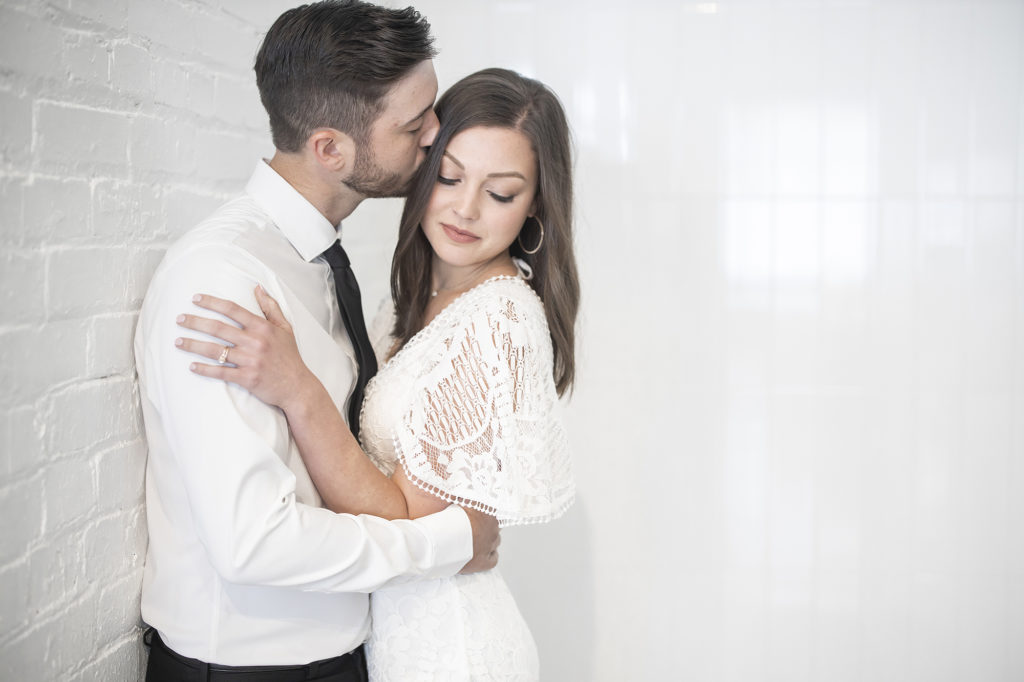 bright airy bride and groom kissing forehead at 1907 building