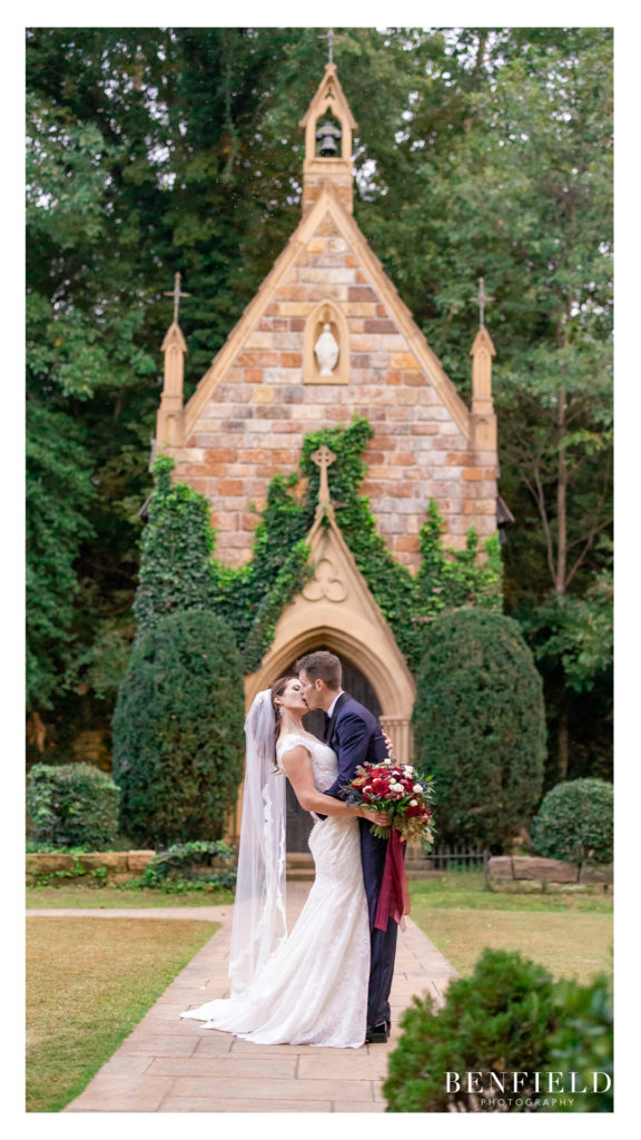 bride and groom kissing in front of a chapel cottage in Arkansas