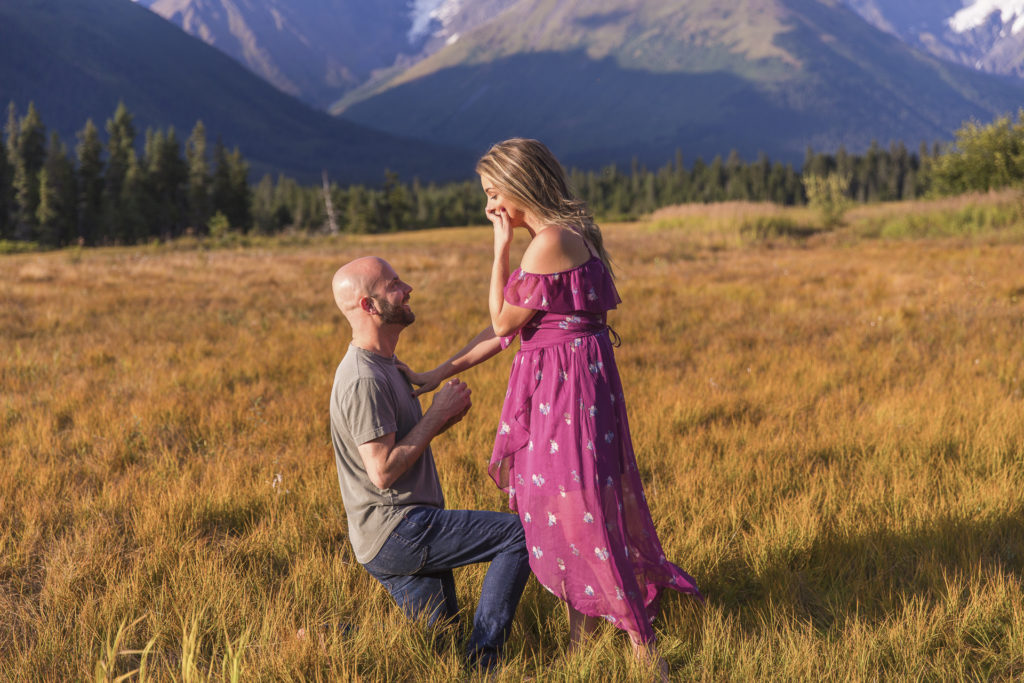 Dale Benfield proposing to Tyler Sowers Benfield with mountains in the background in Alaska