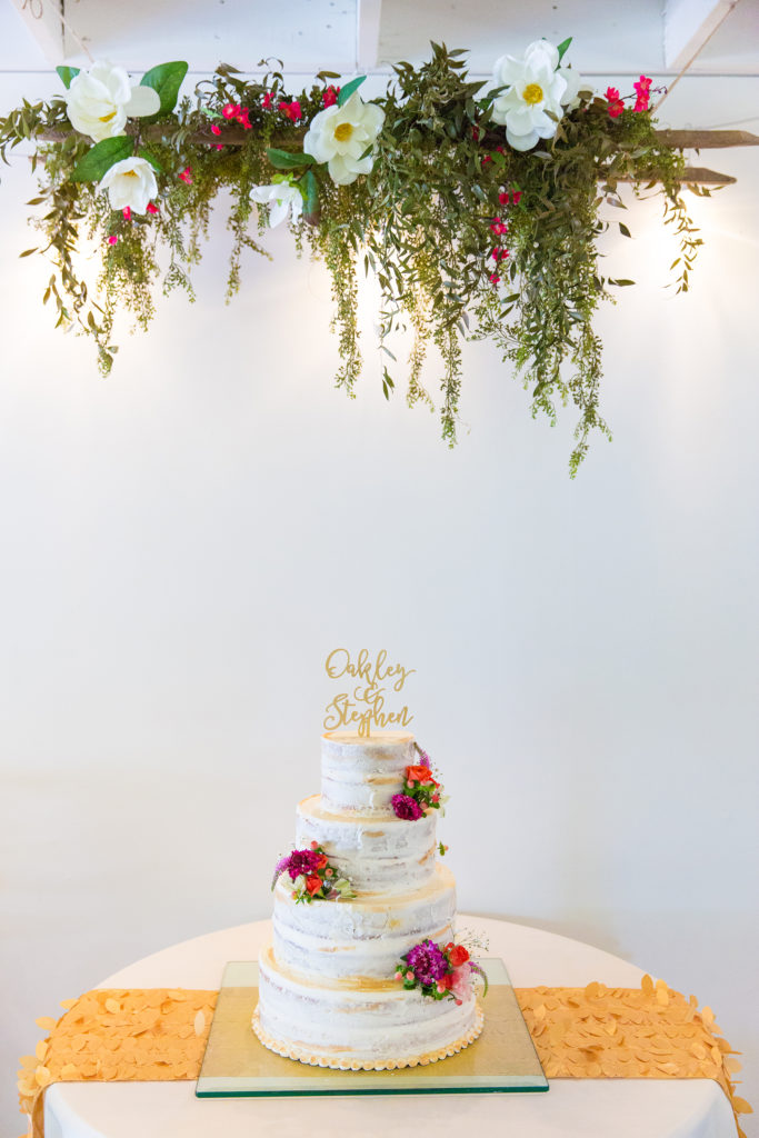 Ths white wedding cake with imperfect white frosting has beautiful floral adornments in the Best Wedding Cake nominee.