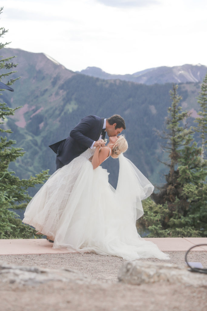 groom dipping bride kissing on top of Aspen Mountain for their wedding
