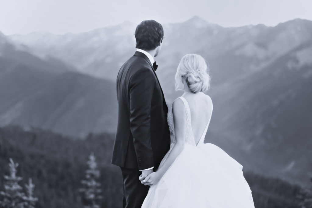 bride and groom gazing from atop their Aspen Mountain Wedding with mountains and forest behind them