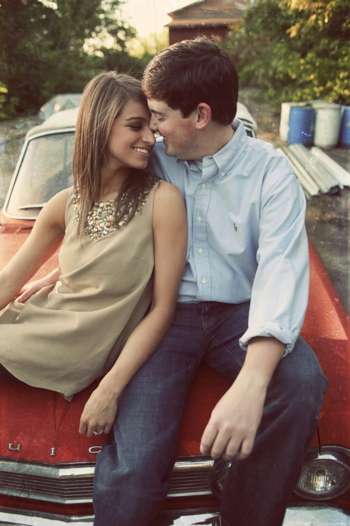 Cute couple sitting on the hood of the car during their engagement portraits
