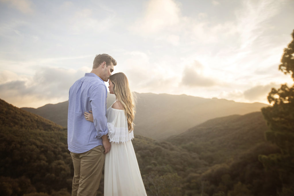 Romantic engagement portrait with groom kissing brides forehead at sunset near the Malibu winery in California.
