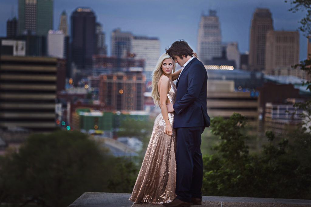 Engagement Photos ideas in downtown Kansas City of formal bride and groom with Kansas City behind them taken at night.