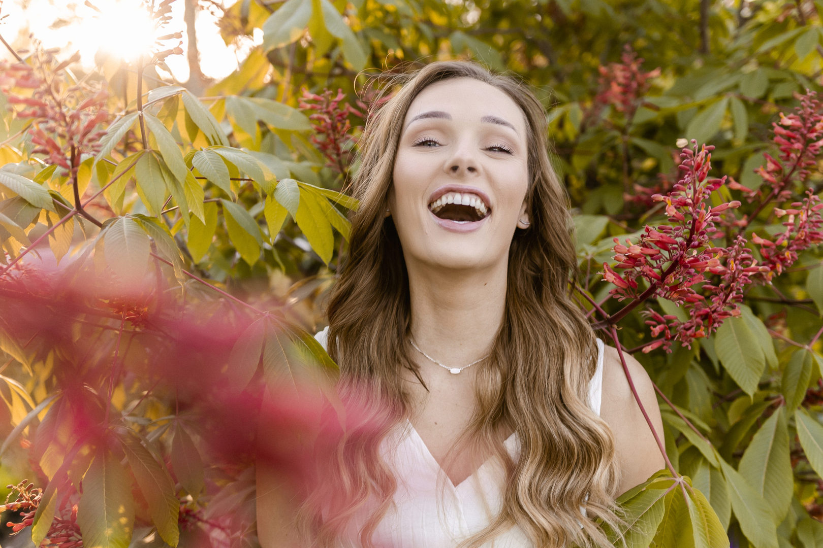 beautiful light skinned girl laughing in a flower bush at Forest Park in St. Louis