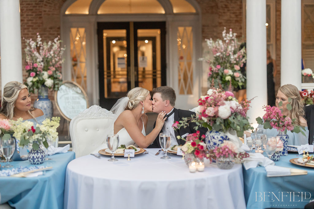 Best Wedding Kisses of 2021 nominee shows a bride and groom sitting at the head table of the reception outside the Inn at Carnall Hall in Fayetteville.