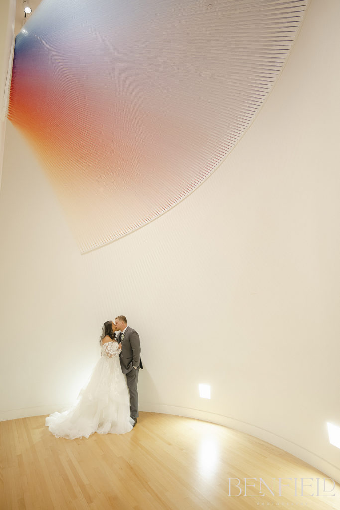 Best Wedding Kisses of 2021 Nominee shows a bride and groom kissing in an art gallery at Crystal Bridges.