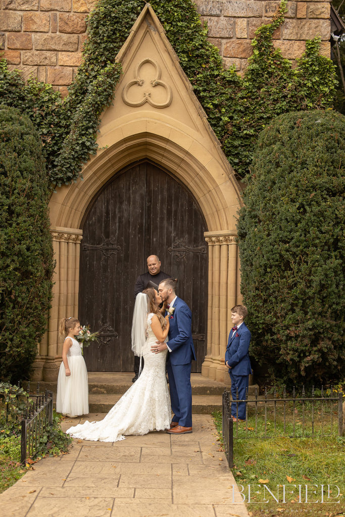 Wedding kiss of bride and groom in front of St. Catherine's Chapel at Bell Gables in Fayetteville.