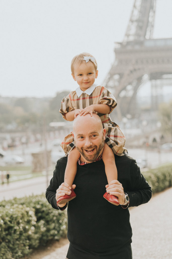 Daddy and Daughter riding on his shoulders in Paris with the Eiffel Tower in the background