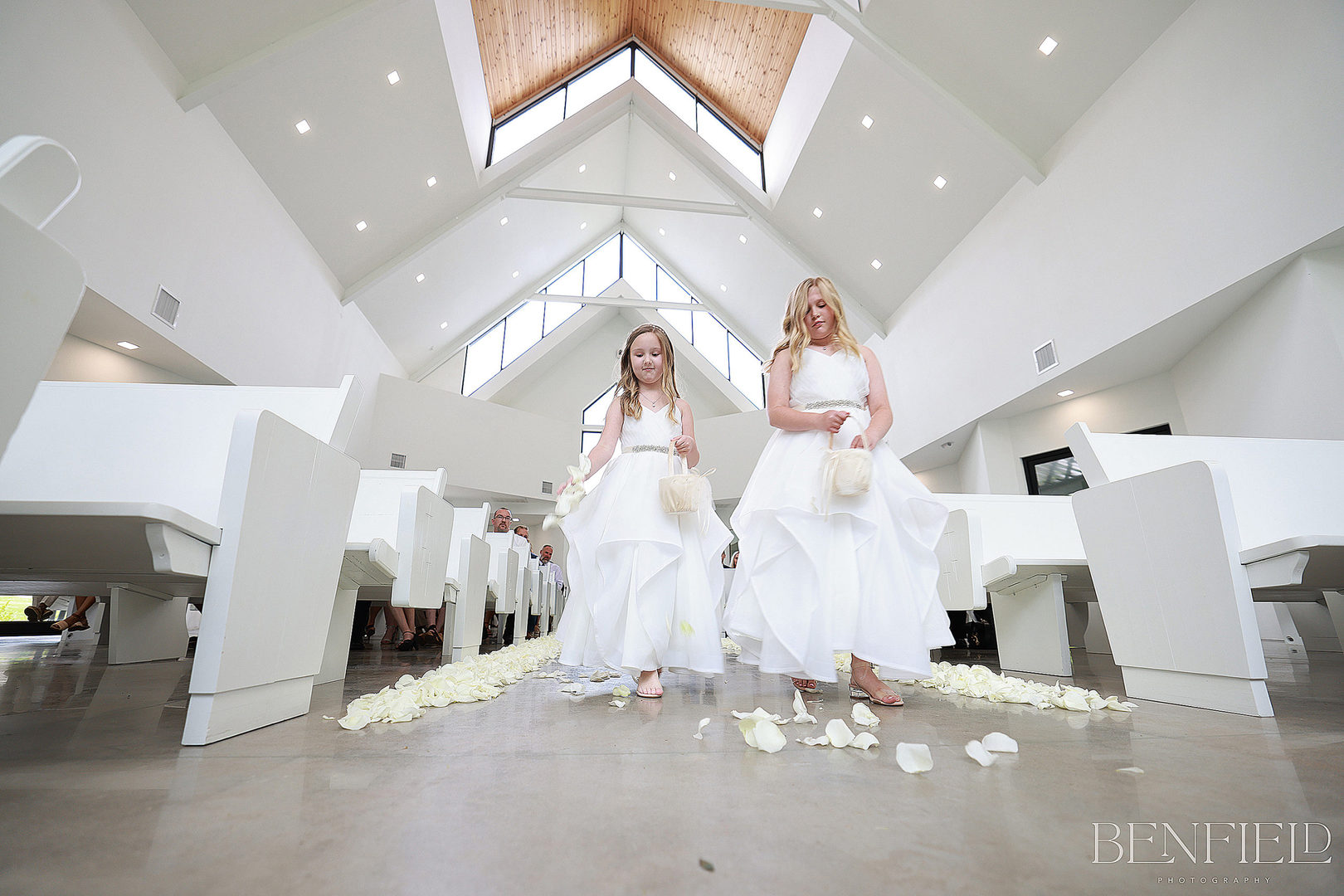 Flower girls walking down the aisle showing the all-white wedding chapel in Arkansas available for Weddings at Osage House