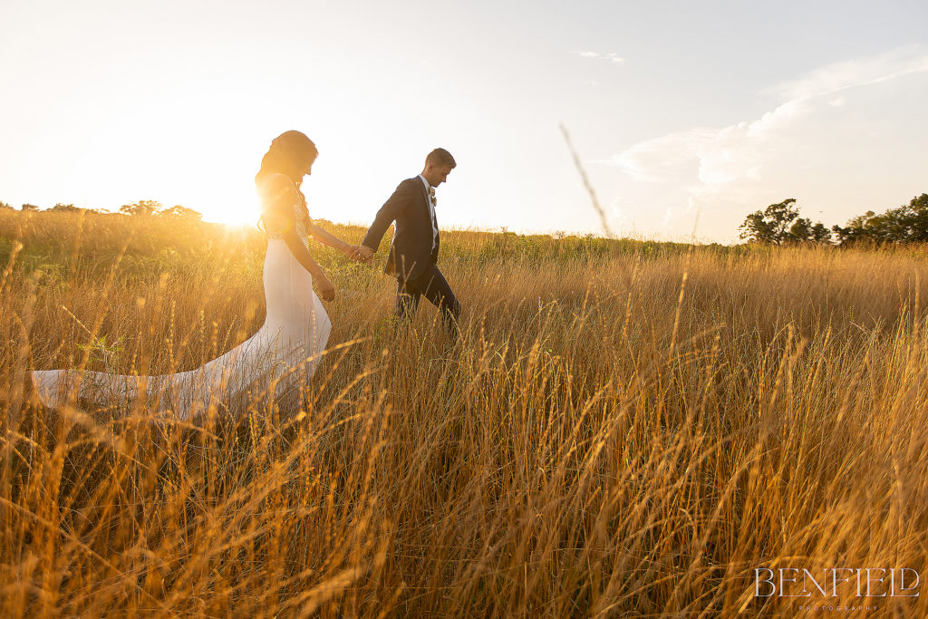 Sunset Weddings at Osage House with bride and groom walking outside in the tall grass during golden hour