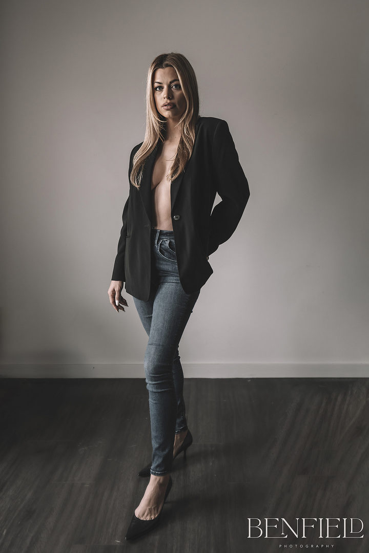 Full body Sexy blonde model wearing no bra and covered with her black suit jacket looking seductively at the camera.