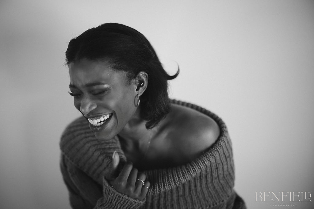 Supermodel Photographer model shoot of black model wearing a loose sweater and no bra laughing hard