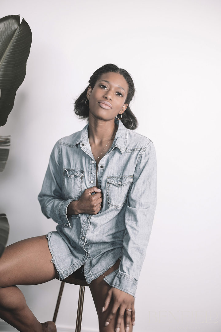 Gorgeous black female model posing with an open denim shirt looking at the camera