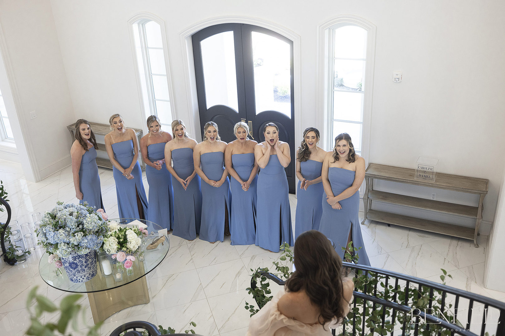 Designer Bride's first look with her bridesmaids on the wedding day as she descends the royal staircase at Hillside Estate in Texas