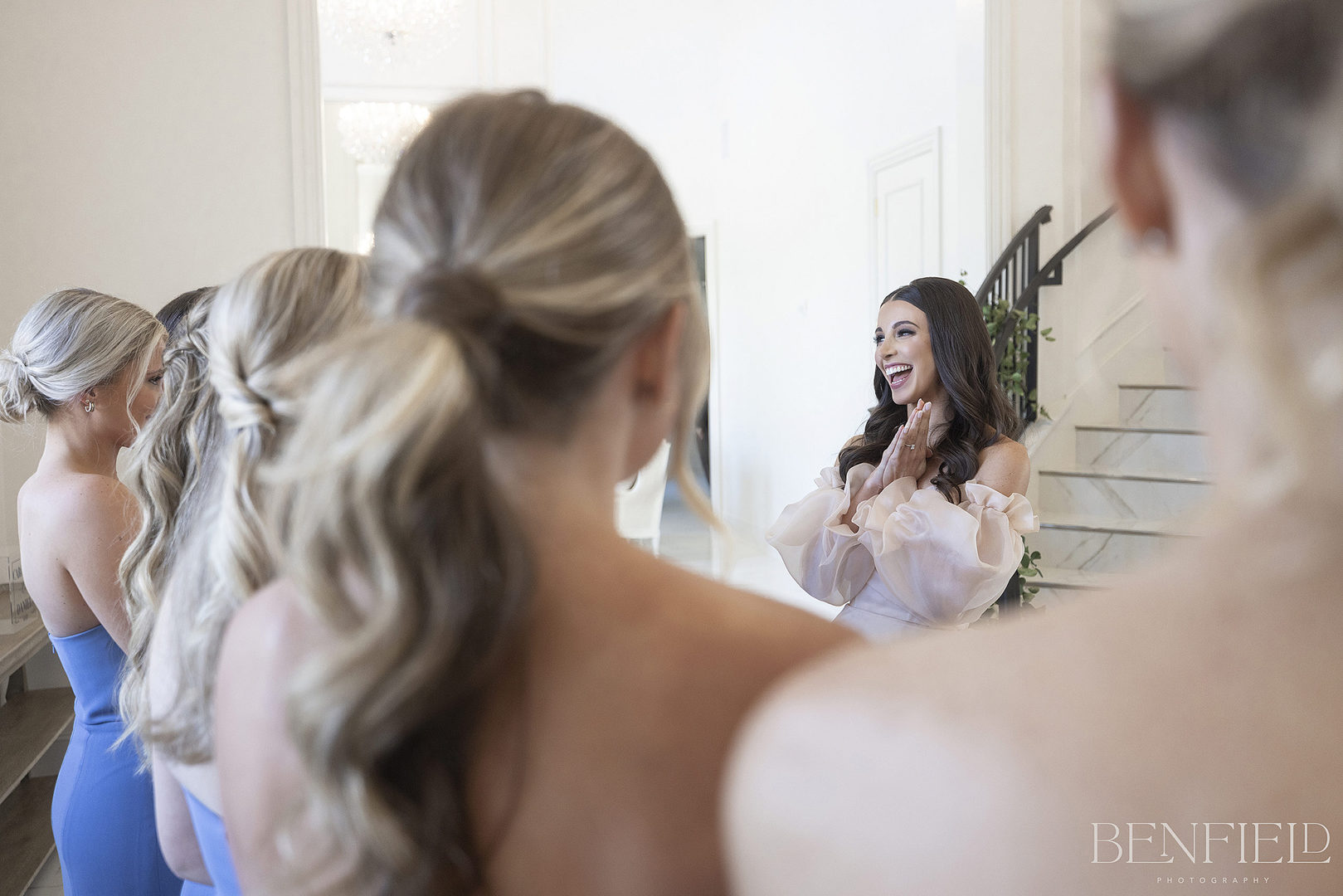 Designer Bride's first look with her bridesmaids on the wedding day as she descends the royal staircase at Hillside Estate in Texas