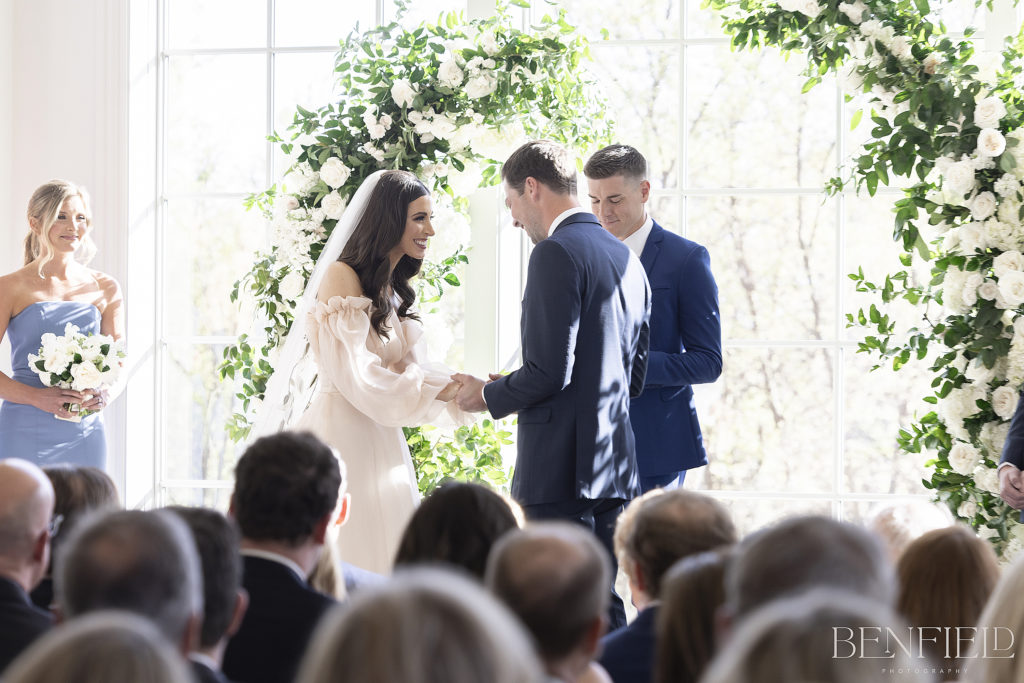 The bride and groom share a laugh during their Hillside Estate Wedding Ceremony in the all white chapel with lots of natural light