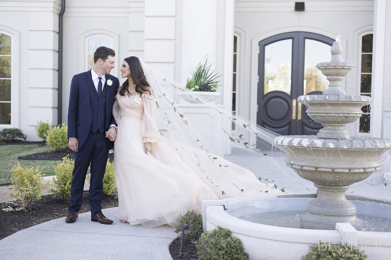 Bride and groom pose near a fountain at Hillside Estate for their wedding portraits.