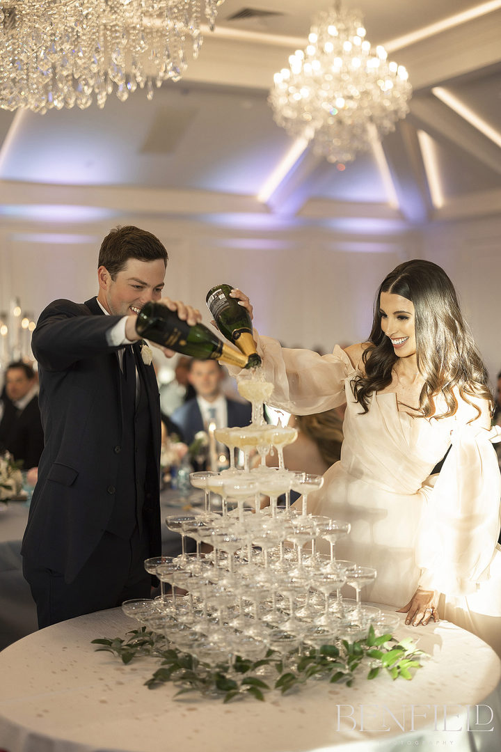 The wedding couple pour two bottles of champagne onto their champagne tower to kick off their wedding reception at Hillside Estate.