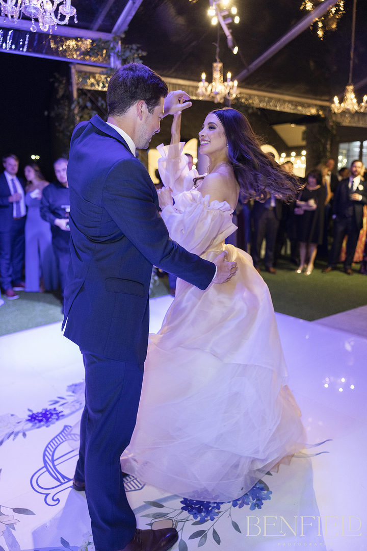 The groom spins the bride on the custom dancefloor for their first dance during the wedding reception outdoors at Hillside Estate