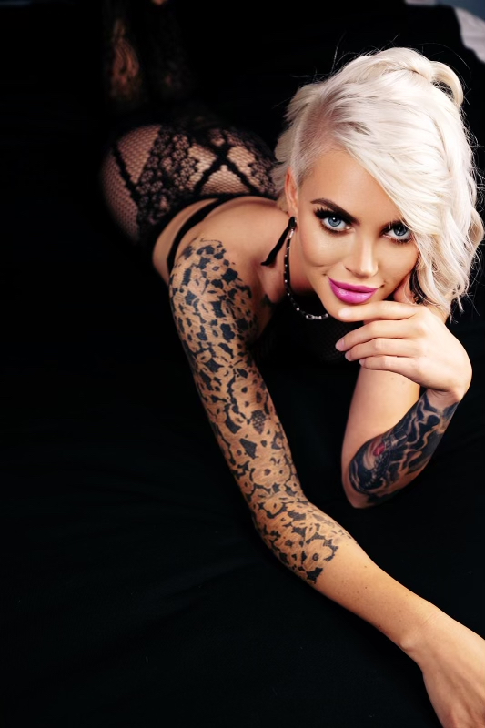 Luxury girl boudoir photos of skinny blonde with tattoos lying seductive on the bed.