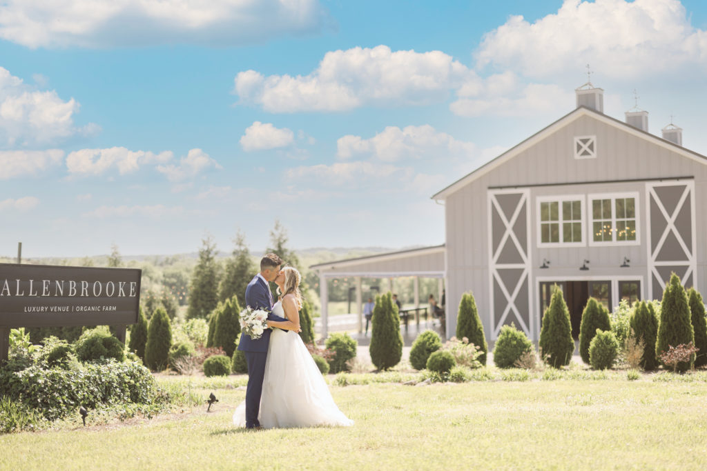 bride and groom kissing in front of Allenbrook Luxury Farms on their wedding day