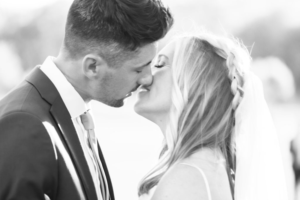 Black and white timeless Wedding Portraits at Allenbrook Farms during golden hour as the bride and groom softly kiss