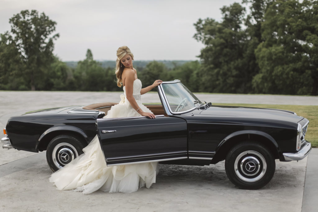 luxury wedding photographer photographs a blonde bride in a designer vera wang gown by a vintage mercedes benz classic car