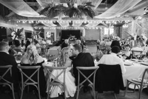 Wedding Reception at Hamp Williams with the bride and groom kissingin the foreground and the guests in the background.