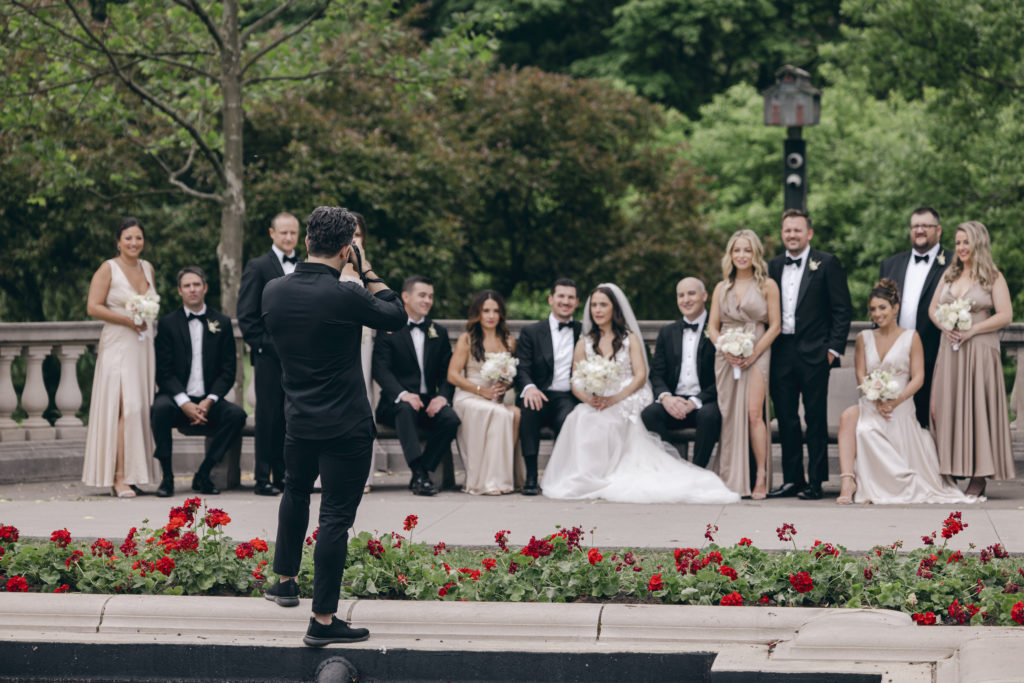 Behind the scenes photo of a photographing shooting the wedding party at the park.