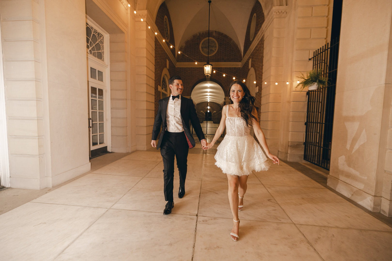 Bridal Jumpsuits and Short Dresses at Wedding Receptions are a fun new wedding trend for 2022 as shown by this bride in her short white dress leading her groom.