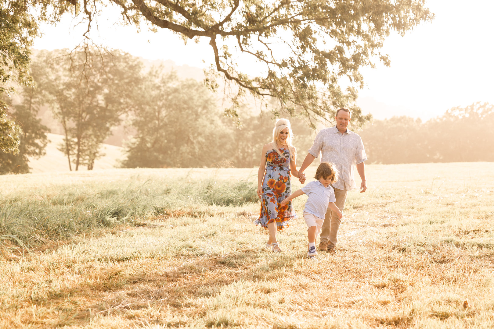 Gorgeous family of 3 portrait during golden hour out in a field in Northwest Arkansas by NWA family photographer Dale Benfield