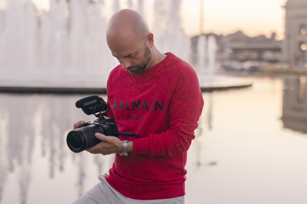 Dale Benfield shoots video and photo stills with his Canon R5C in front of a fountain. 