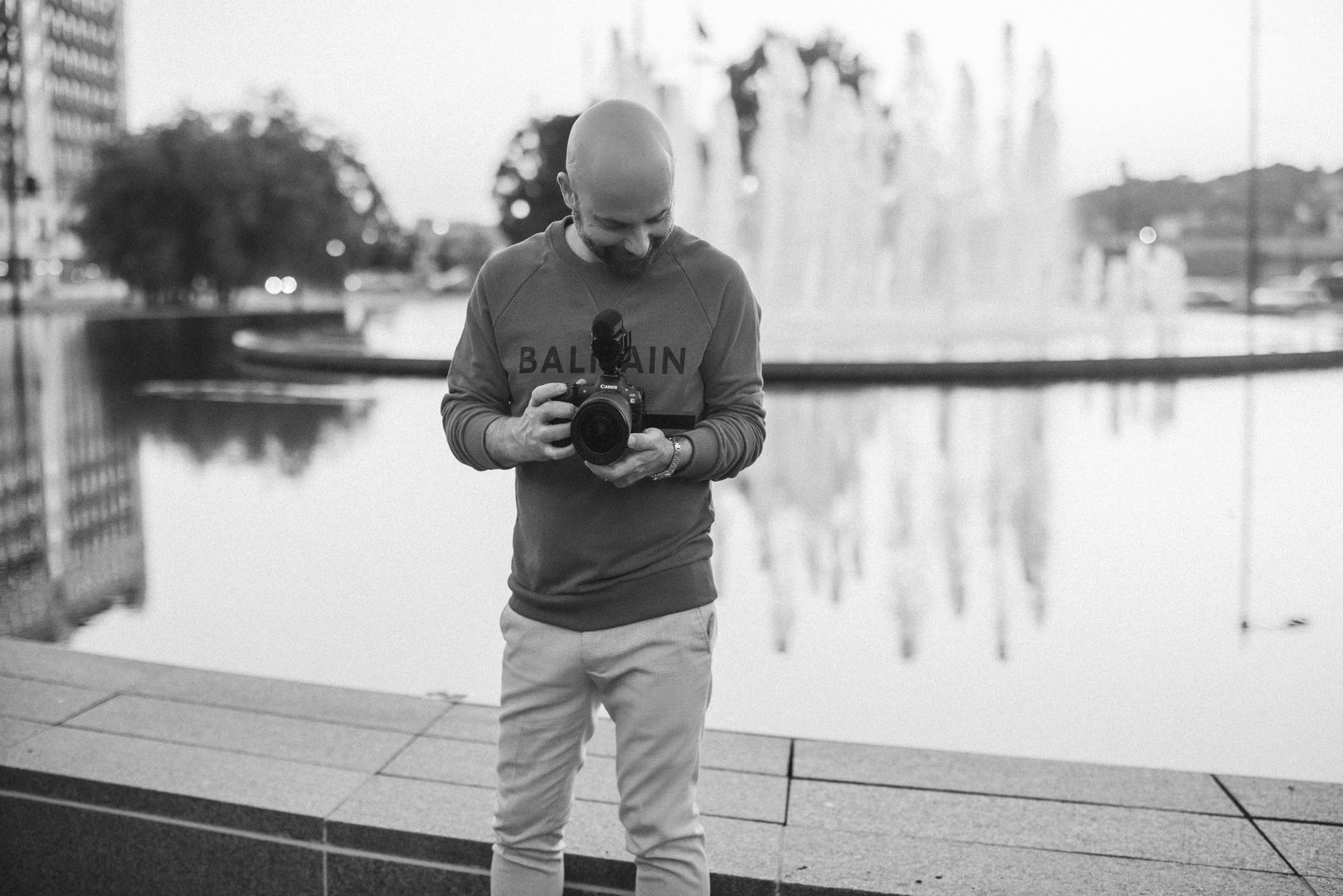 Herding Tigers Book Review by Dale Benfield, seen here holding a camera in front of a fountain in Kansas City.